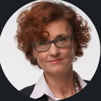 Confident female doctor in glasses and lab coat, sitting on a couch with a stethoscope, looking professional.