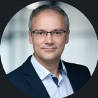 Confident male consultant takes notes, surrounded by legal paperwork in a modern office.
